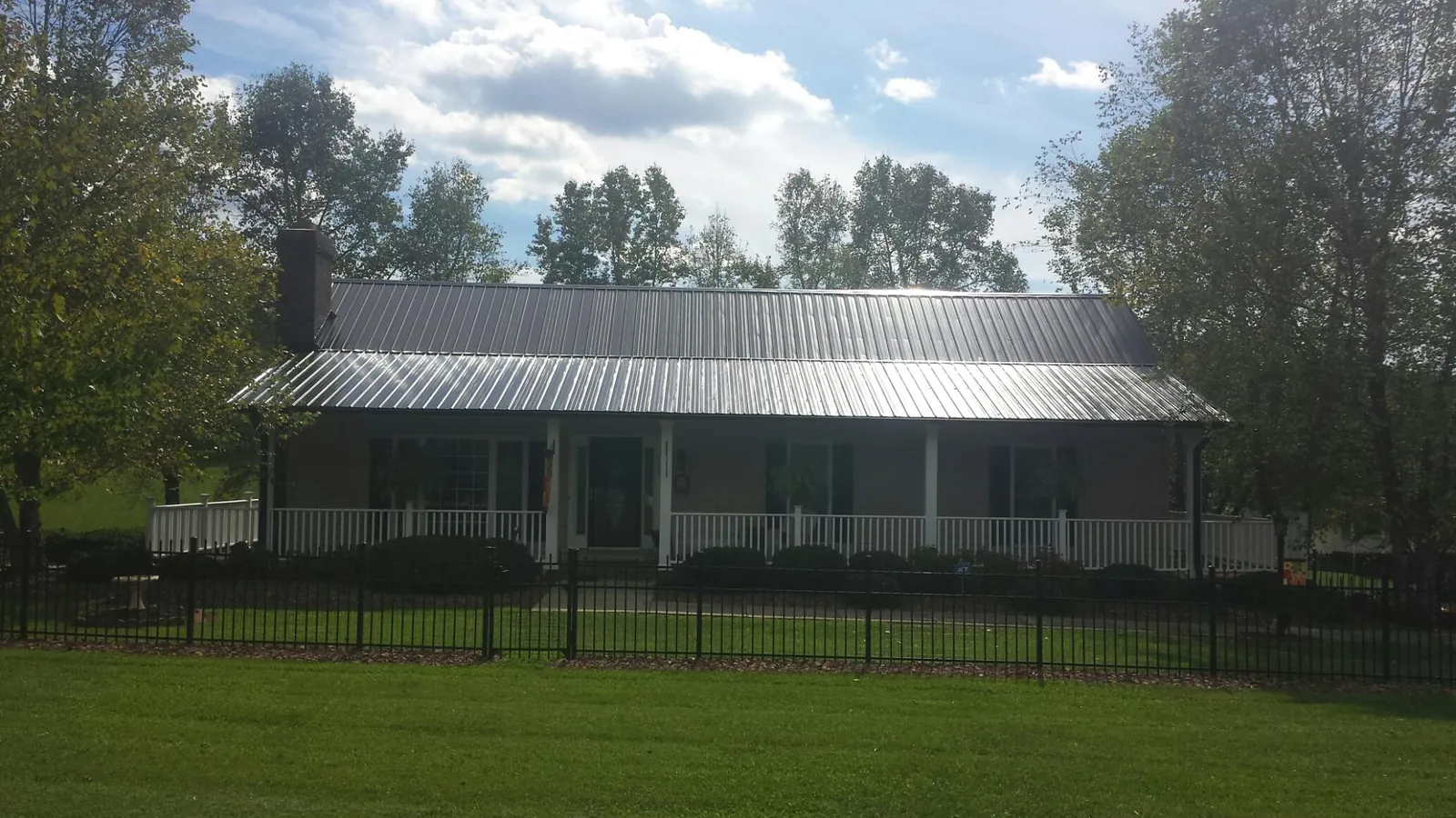 Gray metal roof on a brick ranch with a full width front porch — Gutter Guard Installation work by our crew in Dresden