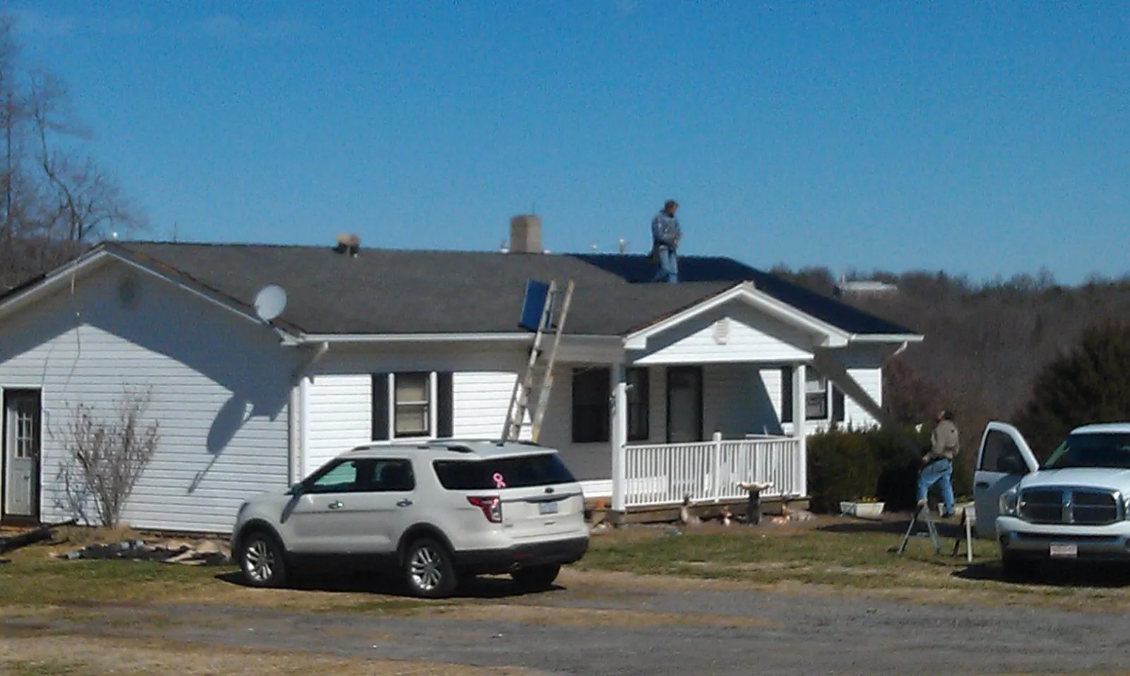 Roofers stripping shingles from a white ranch house roof in Dresden