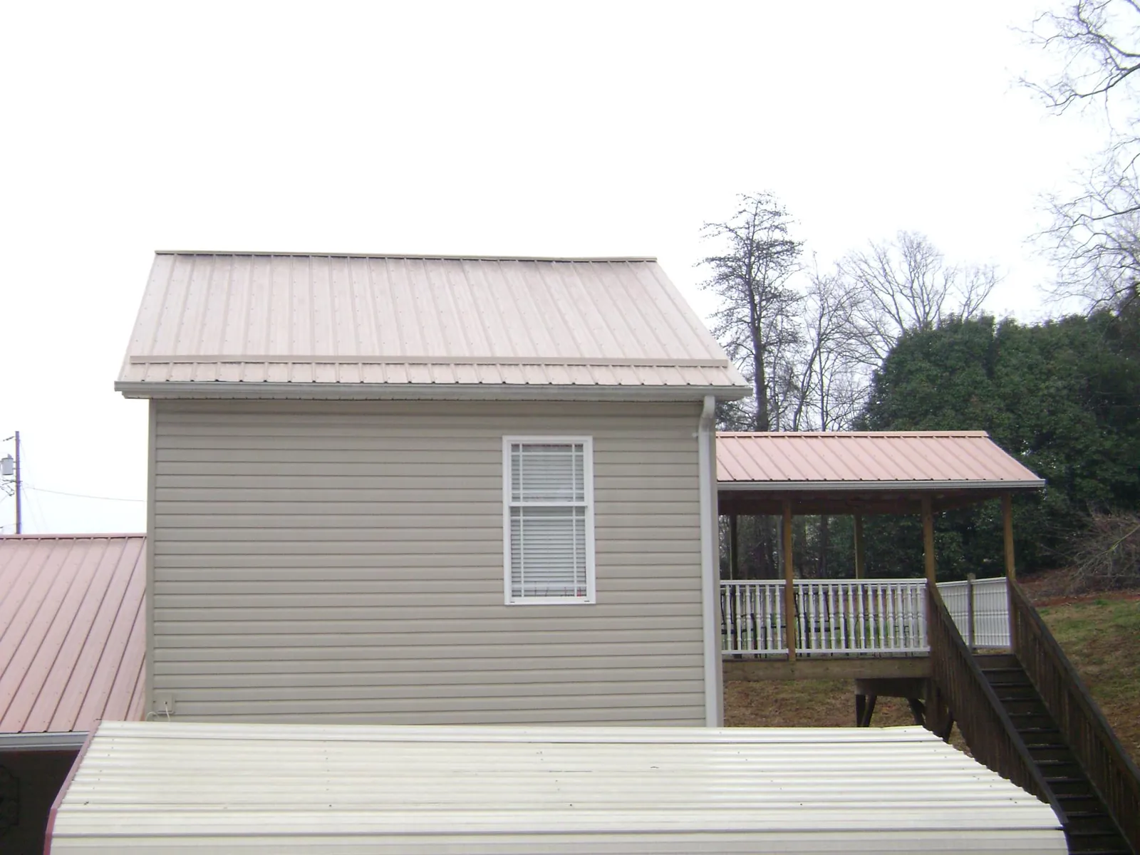 Tan metal roofs on a two story addition and attached porch, from a Roof Replacement job in Dresden