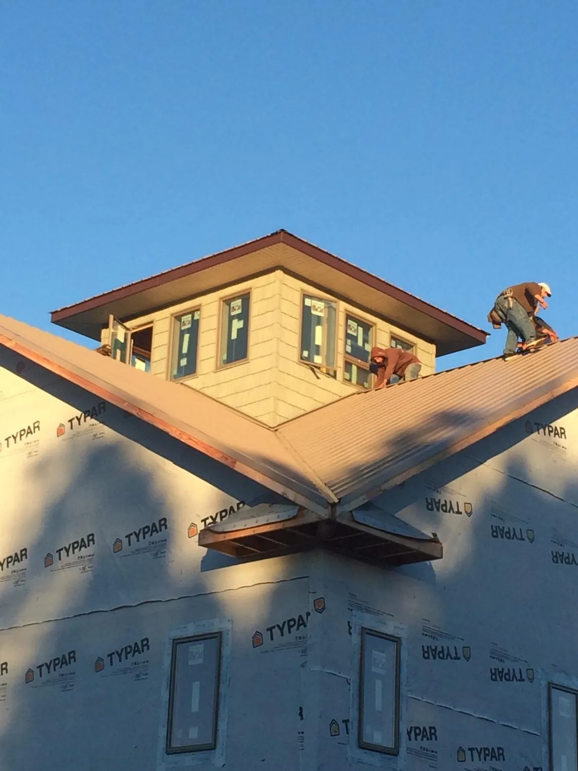 Roofers working around a rooftop cupola on a new metal roof at sunset — Roof Waterproofing in Dresden by Roofing Brothers